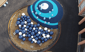 Legeplads med legebakker i helstøbt gummibelægning og et balanceforløb med hoppestubbe i termoplast ved Aakjær Torv i Skive.