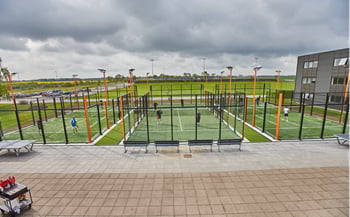 Tre udendørs padelbaner i BGI Akademiets orange farver med farvede hjørnesøjler og lysmaster.